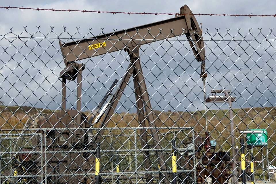 A machine is pumping oil from the underground enclosed by chain link fence.