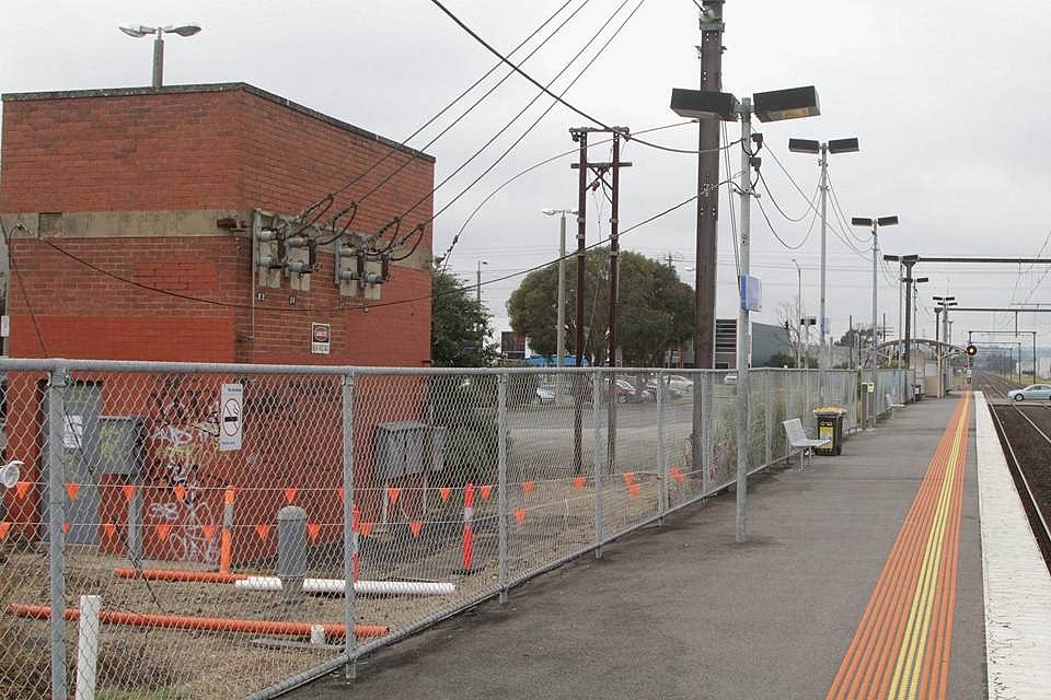 Railway tracks are enclosed by galvanized chain link fence.