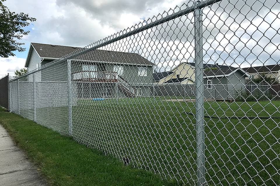 Several residential houses are enclosed by galvanized chain link fence.