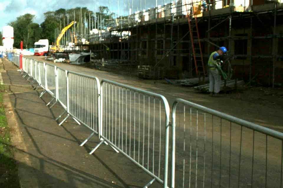 A worker is handling materials on the building construction site surrounded by crowd control barrier.