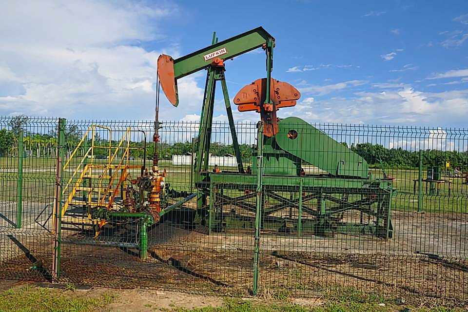 An oil developing machine is parked in the yard enclosed by curvy welded fence.