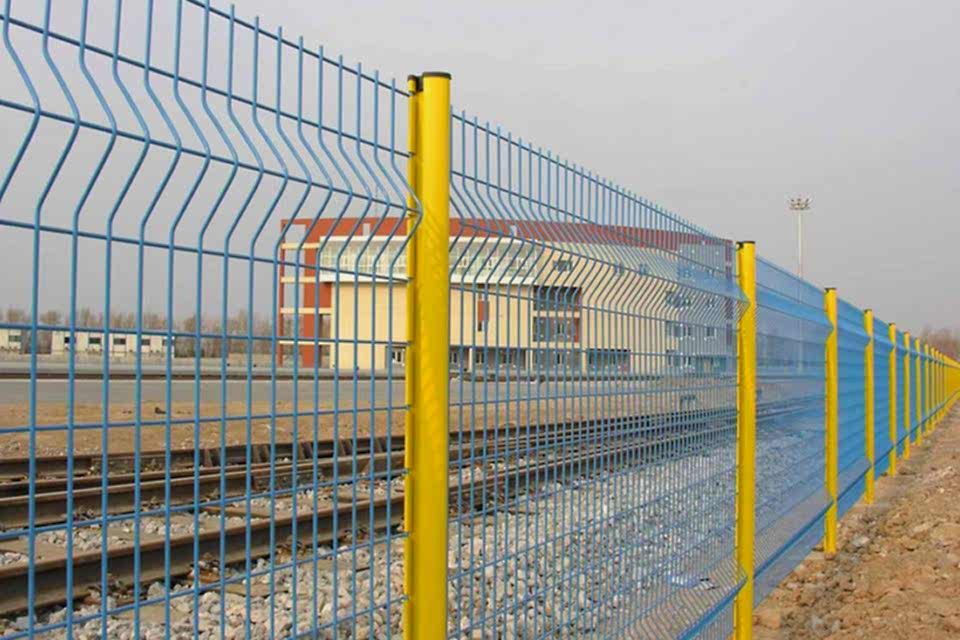 Railway tracks and an office room are encircled by curvy welded fence.