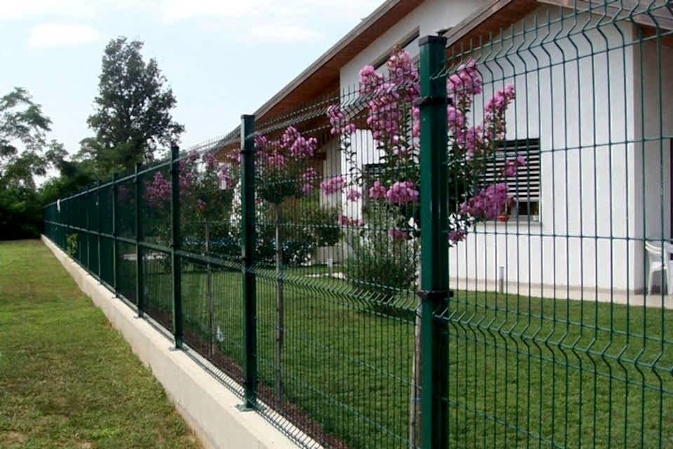 Flowers are planted in the yard encircled by curvy welded fence.