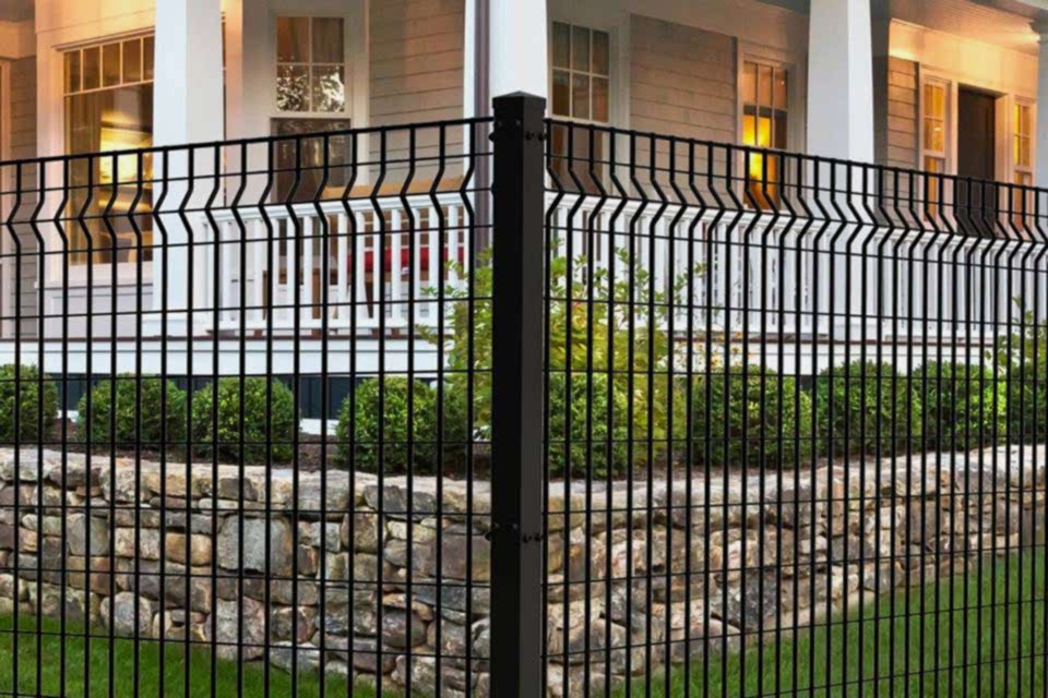 A well-decorated house yard is enclosed by curvy welded fence.