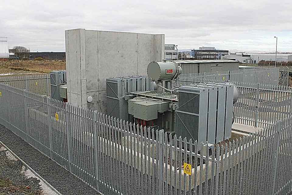 A substation is established in the open air and enclosed by palisade fencing.