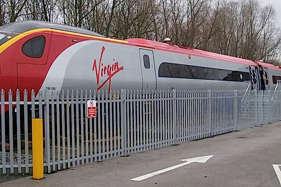 A train is running on the railway track placed along the palisade fencing.