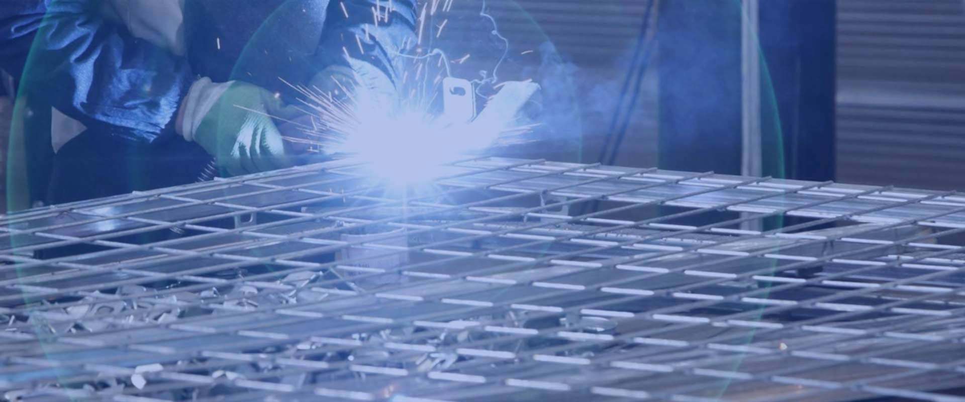 The worker is welding the wire mesh panel.